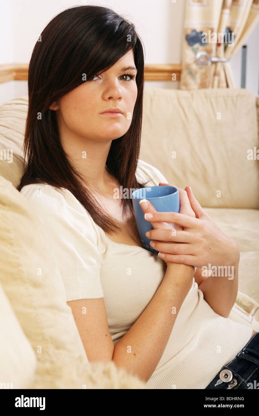 Pretty Dark Haired Woman Sitting At Home Holding A Coffee Cup Stock