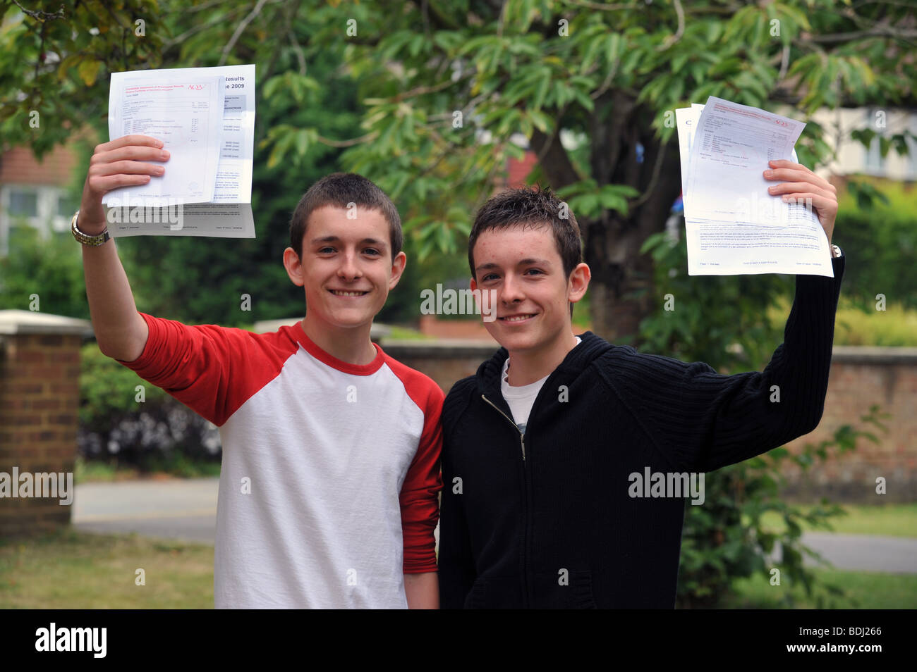 Two twin brothers holding up their successful A star GCSE O level