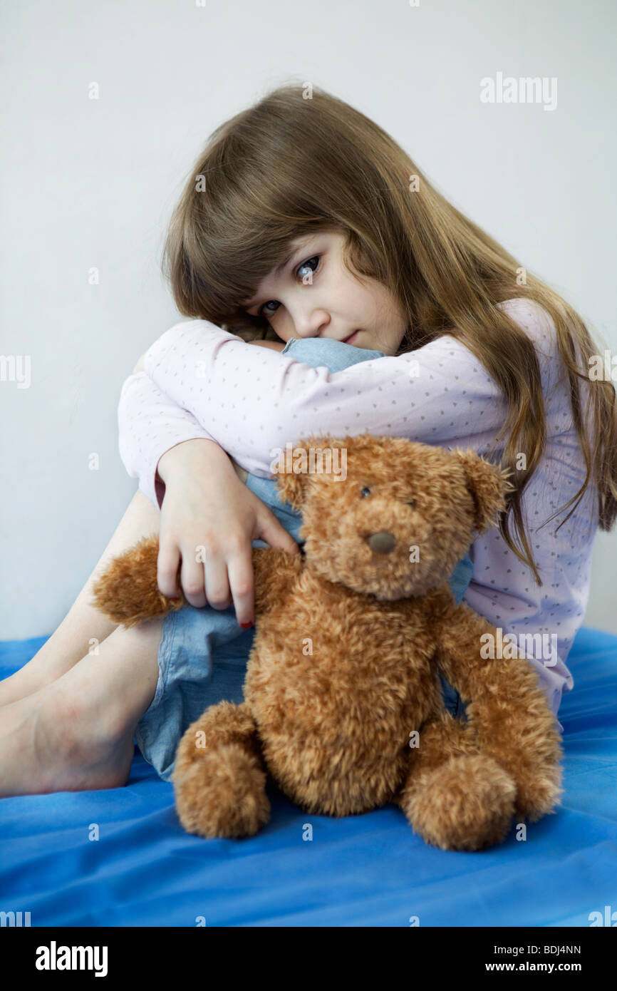 little cute sad girl eight years old sitting on sofa with her ...