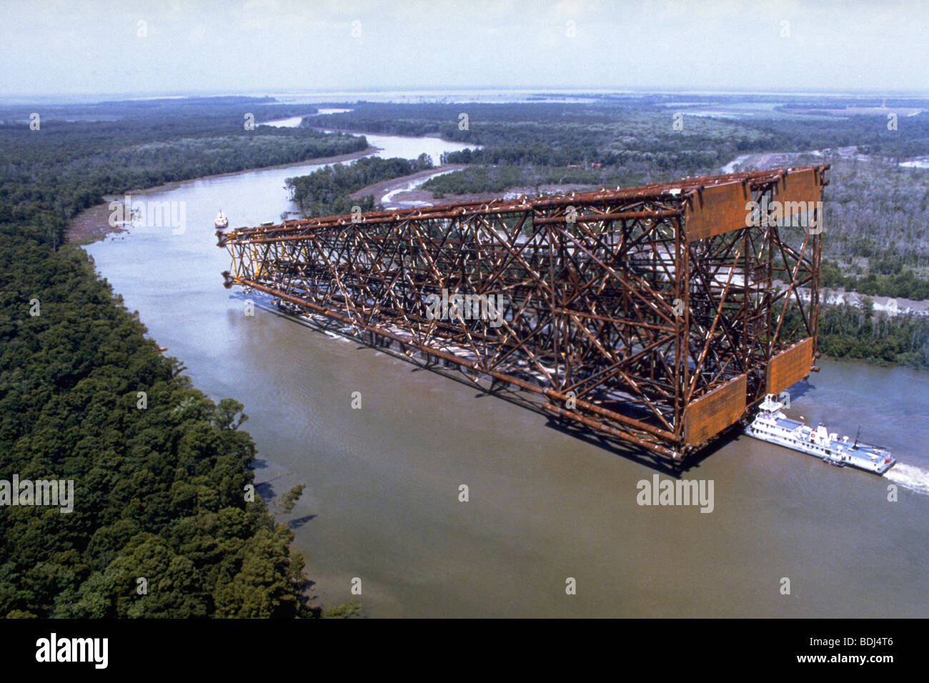 Off shore oil rig, oil jacket being floated down river on barge to gulf