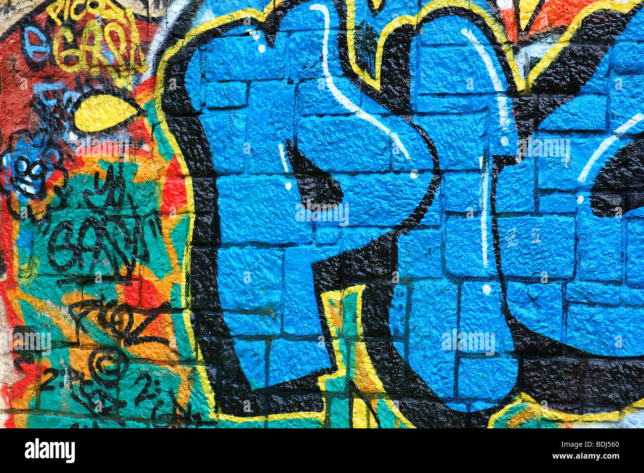 Rough wall surface covered with colorful graffiti. Urban street art background. Stock Photo