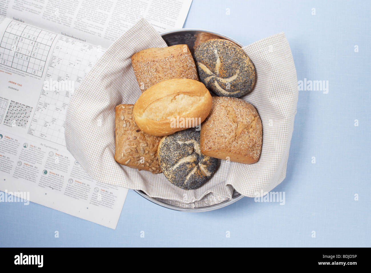 Bowl of Various Bread Rolls with Newspaper Stock Photo