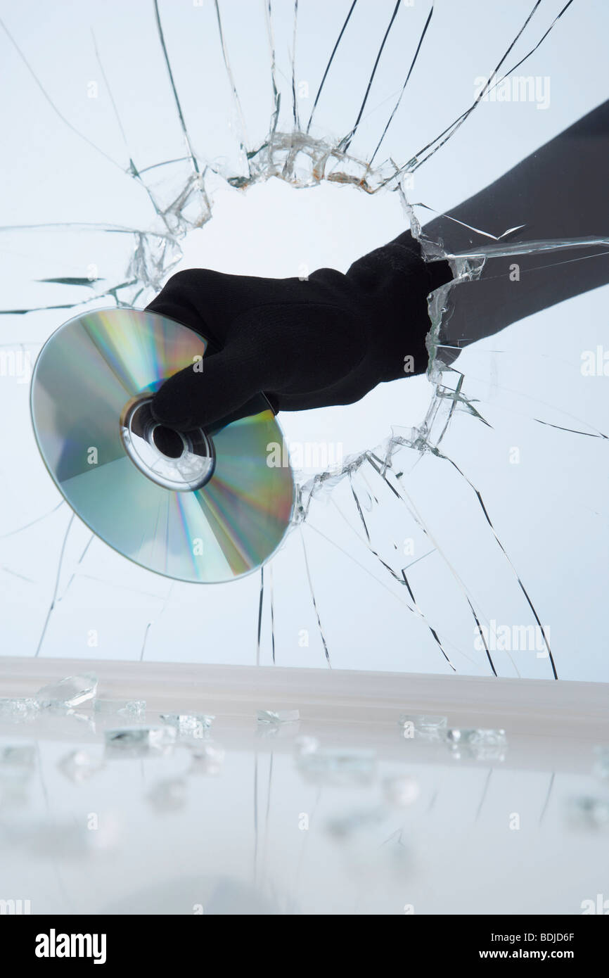 Hand Stealing CD Through Broken Glass Stock Photo
