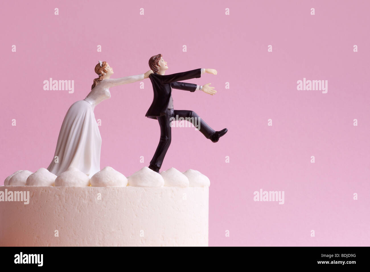 Wedding Cake Figurines, Bride Grabbing Runaway Groom Stock Photo