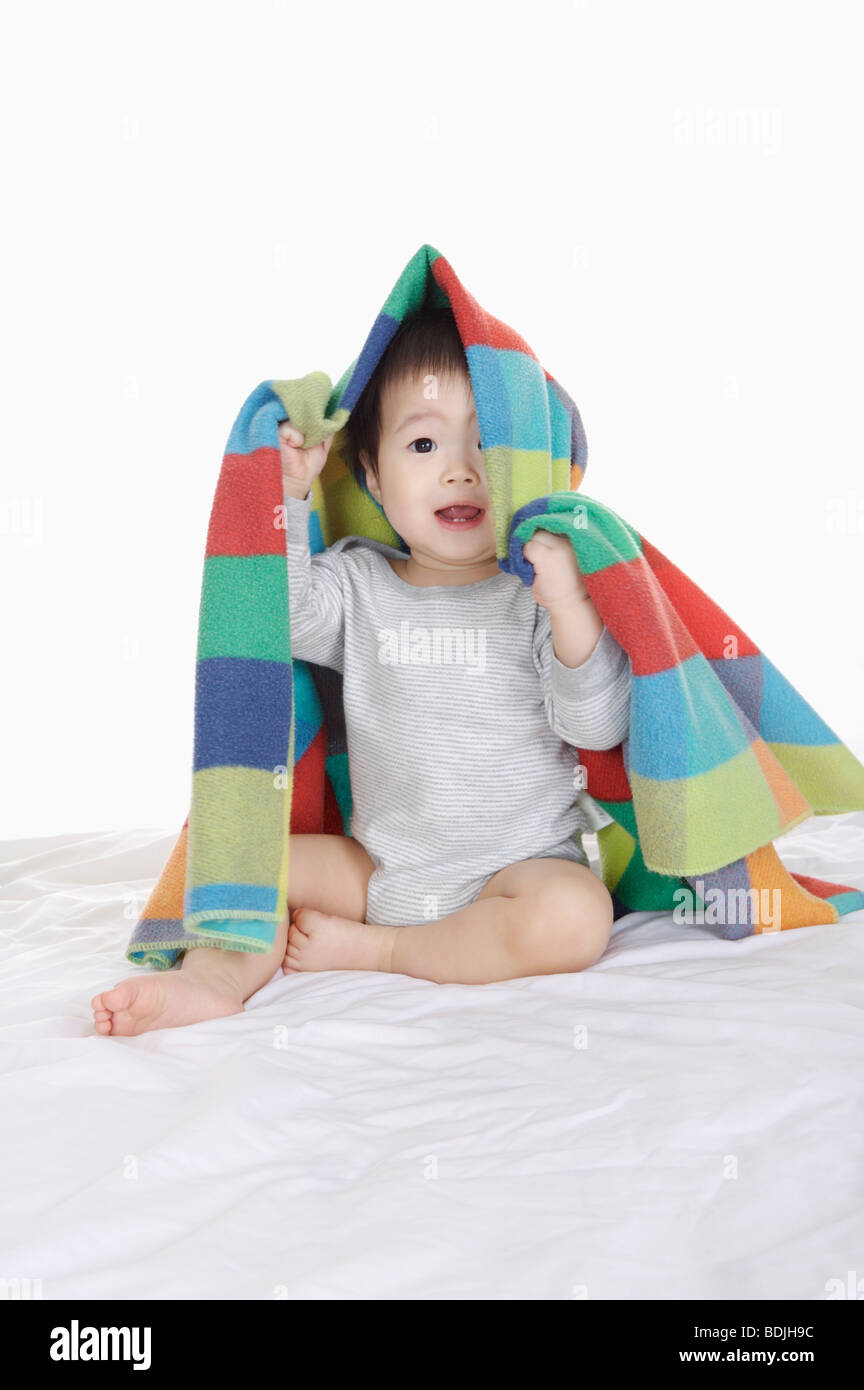 Baby girl sitting and holding a blanket on head,Child Stock Photo Alamy
