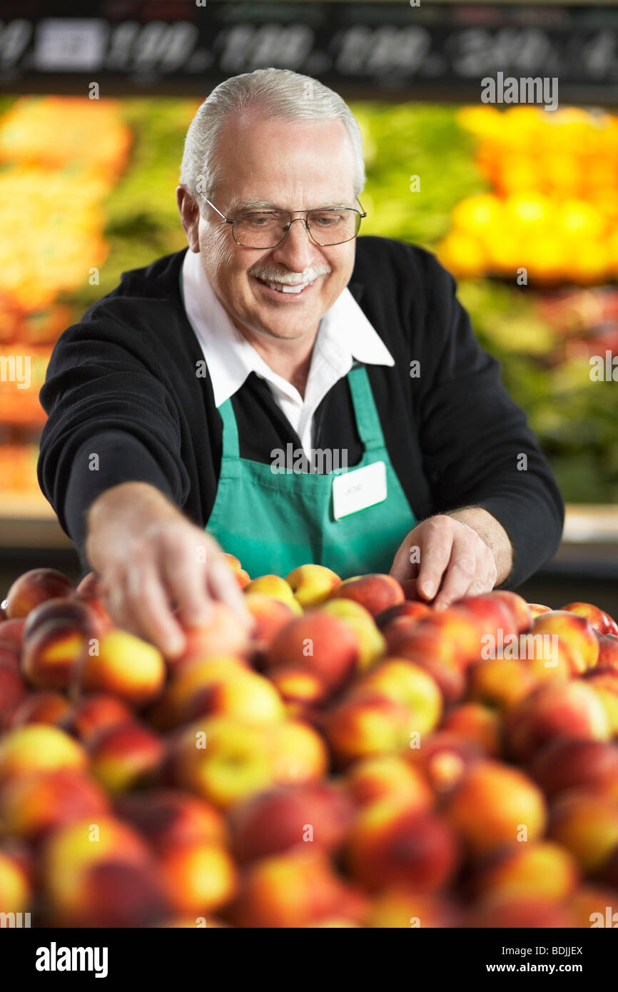 Grocery Clerk Arranging Peaches in Produce Aisle Stock Photo