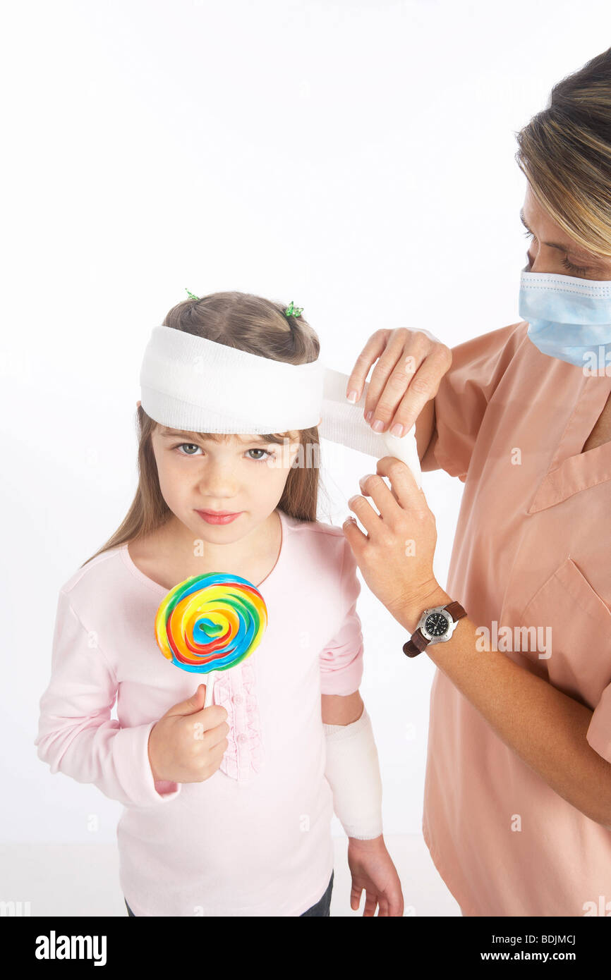 Nurse Wrapping Bandage Around Girl's Head Stock Photo