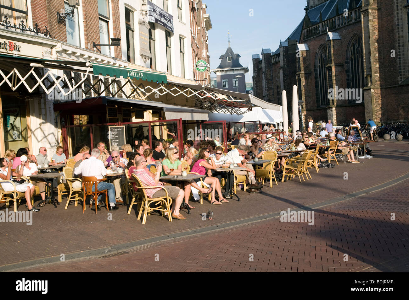 People outside at cafe tables and chairs, Grote Mart, Haarlem, Holland Stock Photo