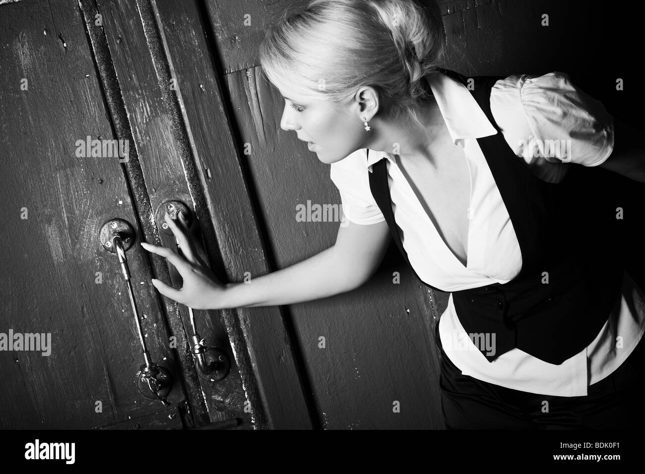 Young woman touching old door. Black and whie. Stock Photo