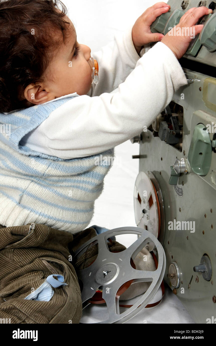 Young child of one playing with a old style tape recorder with dummy in mouth. Model release available Stock Photo