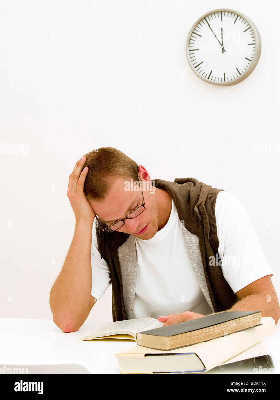A young student working on his homework while the clock is ticking