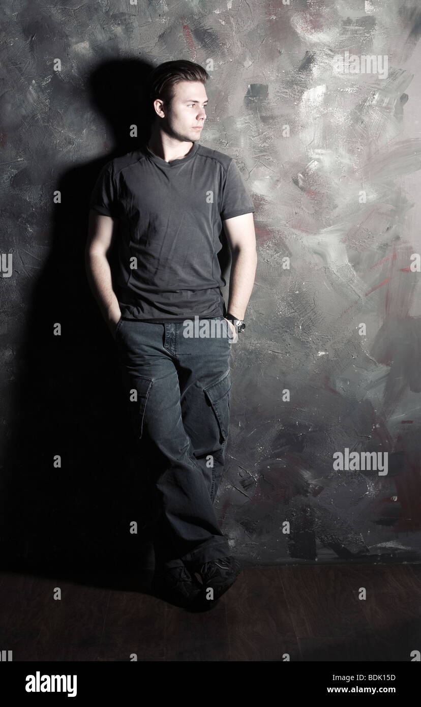 Young man standing on wall background Stock Photo - Alamy