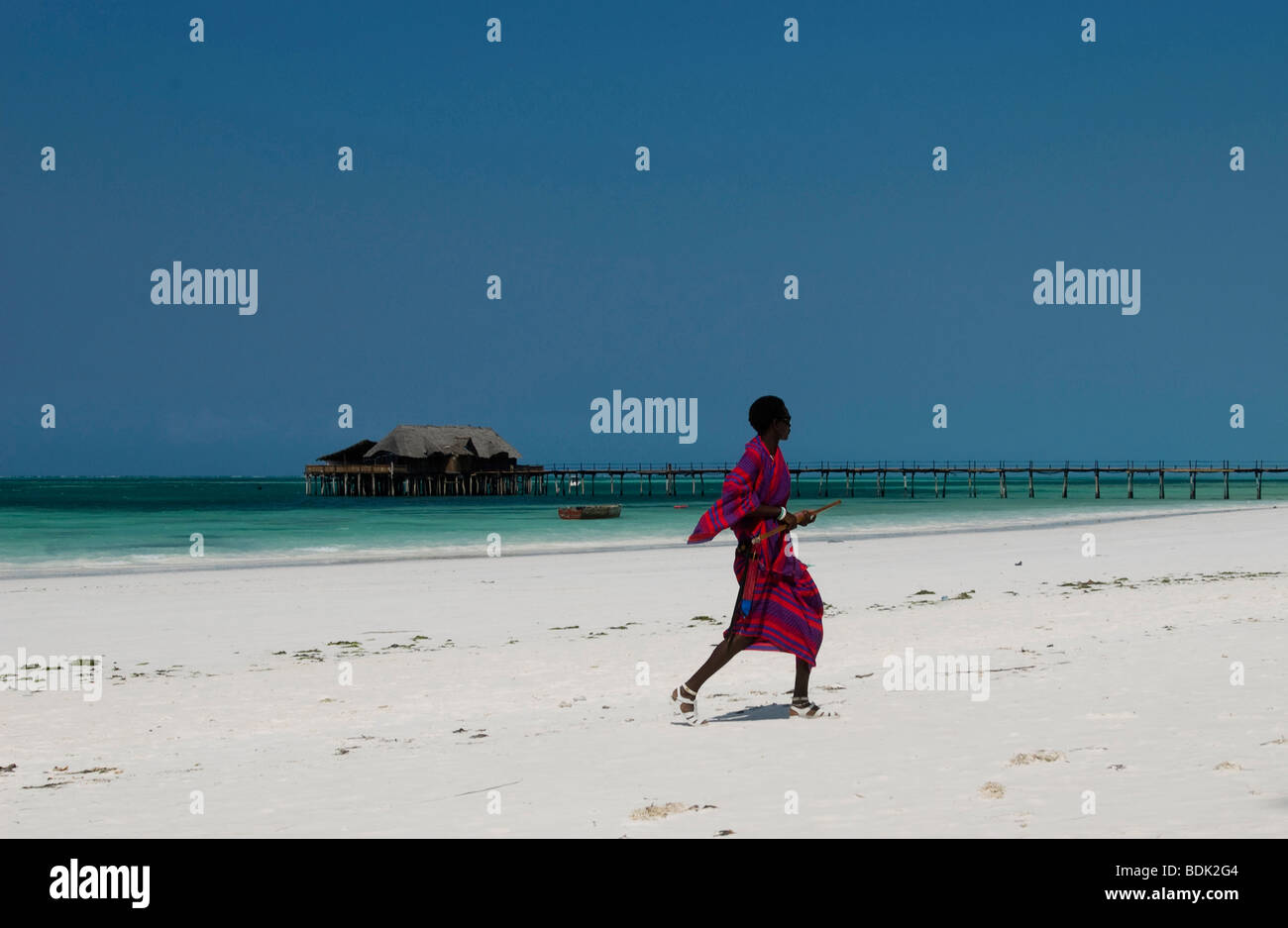 Colorfully dressed Swahili man walking on Zanzibar beach Stock Photo