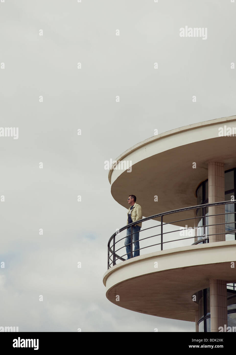 man standing on curved handrail balcony of Bexhill pavilion looking out towards English Channel Stock Photo