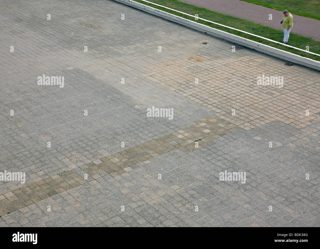 woman looking at grass verge pavement expanse alone open space Stock Photo