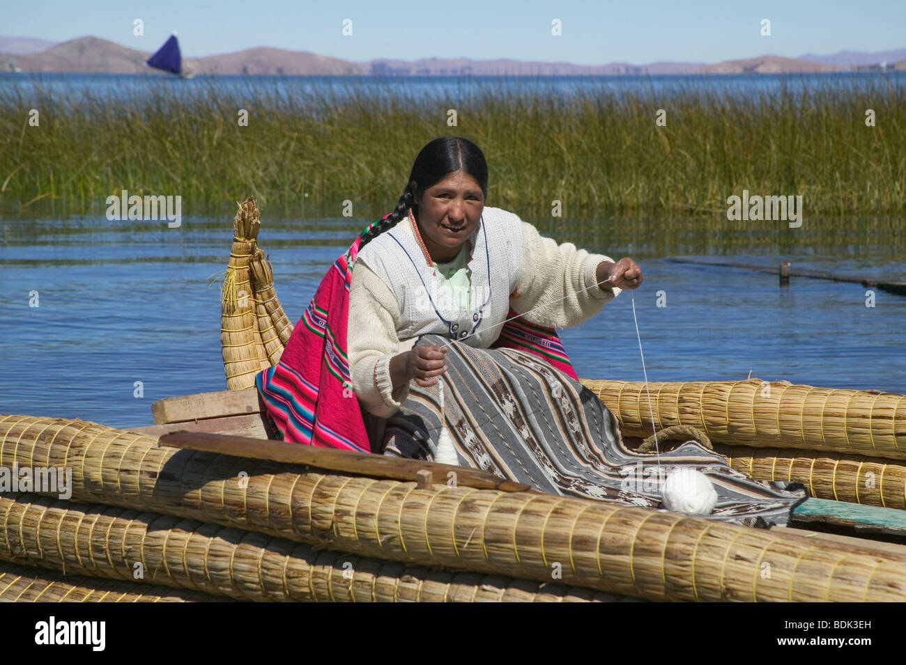 Indian woman doing needlework on reedsmade canoe on Lake Tititicaca