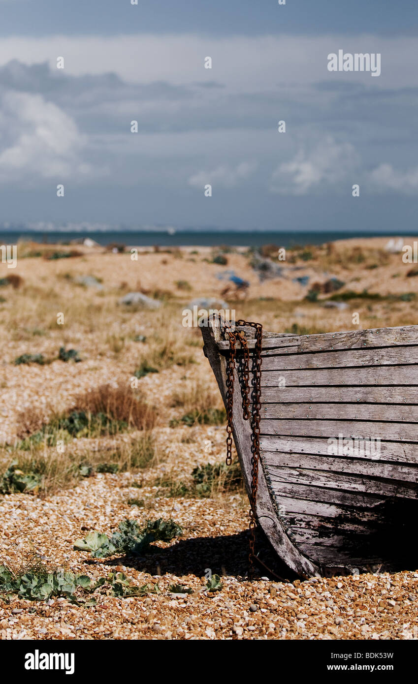 An abandoned wooden boat on the shingle beach at Dungeness in Kent ...
