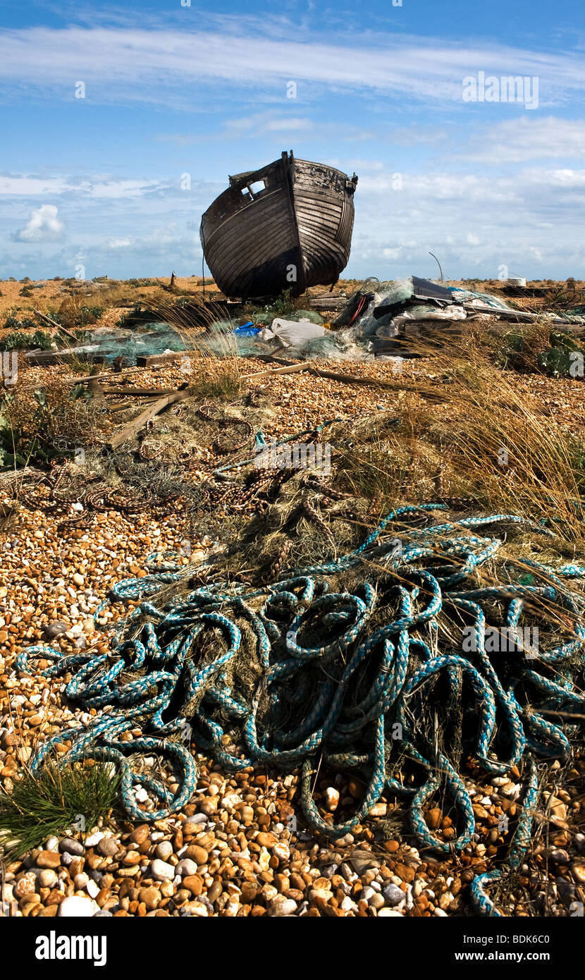 An abandoned wooden fishing boat beached on the shingle beach at ...