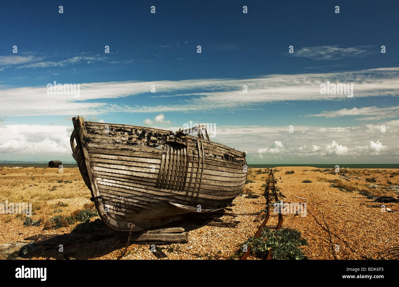 An abandoned wooden fishing boat beached on the shingle at Dungeness ...