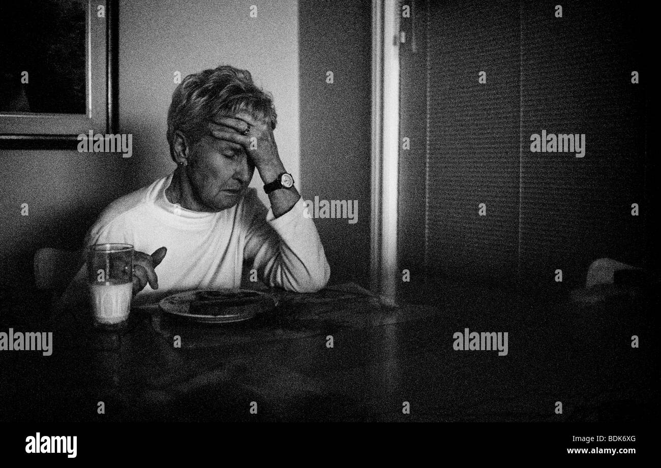 Distressed elderly woman sitting at kitchen table Stock Photo Alamy