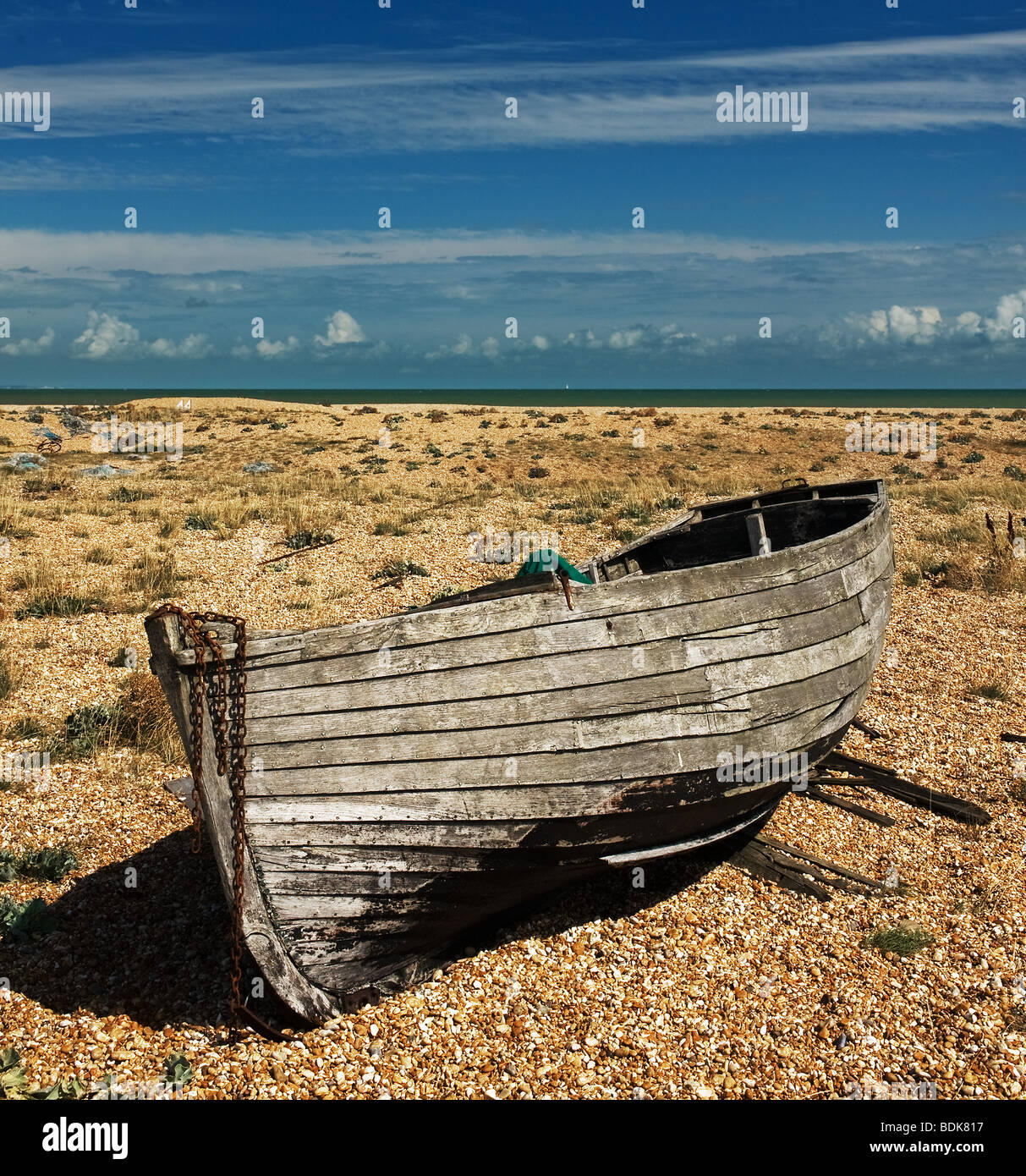 An abandoned wooden fishing boat beached on the shingle at Dungeness in ...