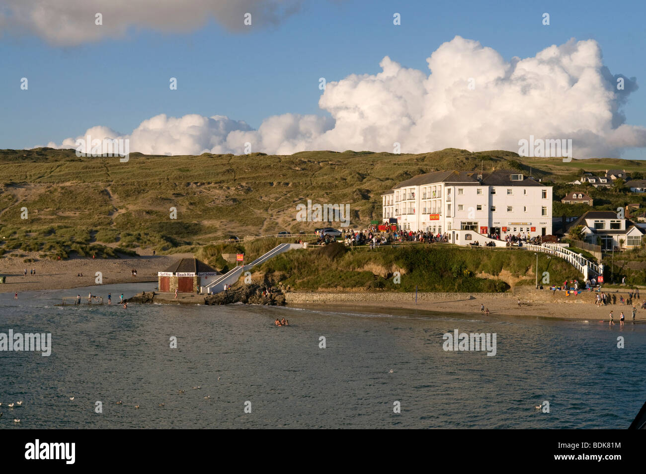 Holiday makers on beach in front of Ponsmere Hotel and Sunset Bar in