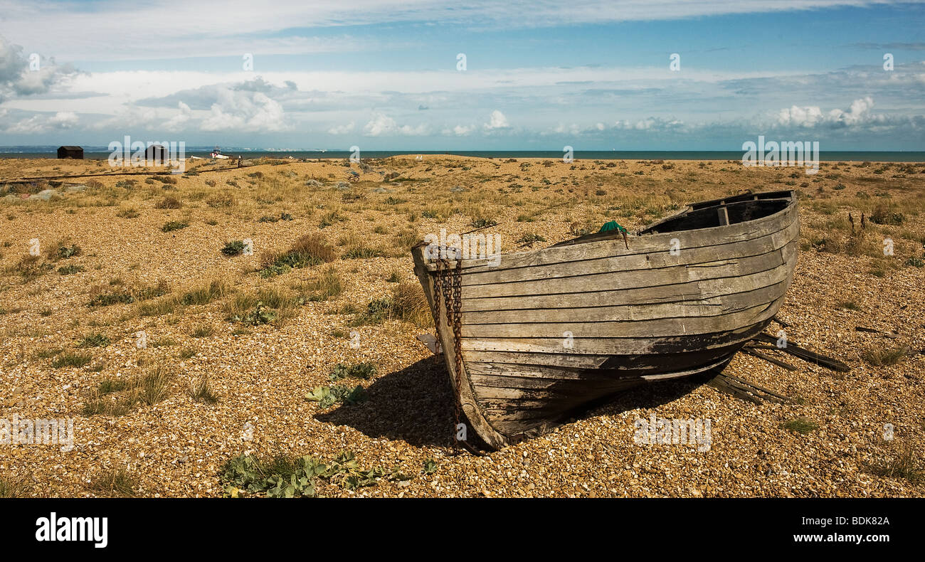 An abandoned wooden fishing boat beached on the shingle at Dungeness in ...