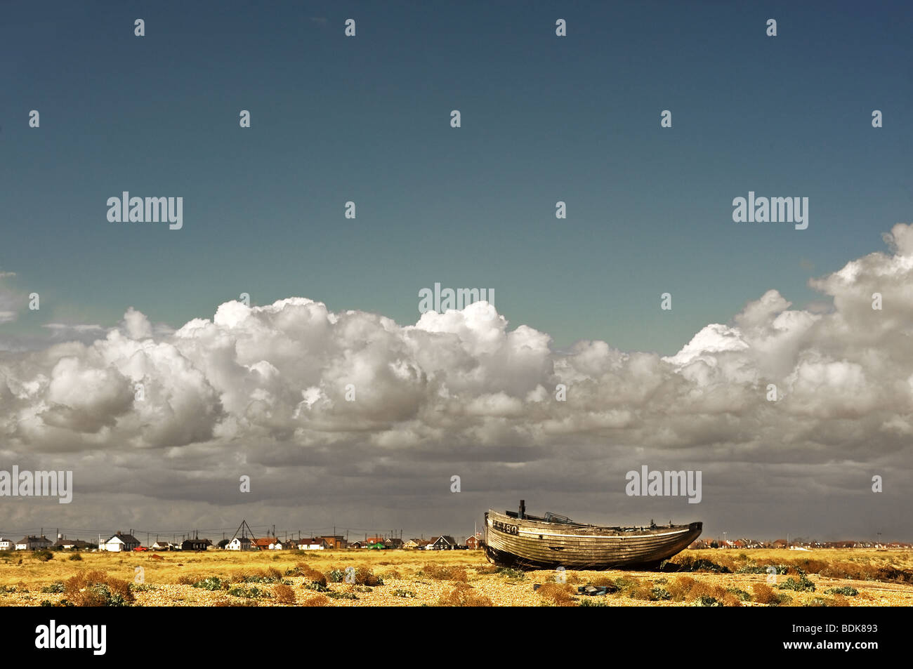 An abandoned wooden fishing boat beached on the shingle at Dungeness in ...