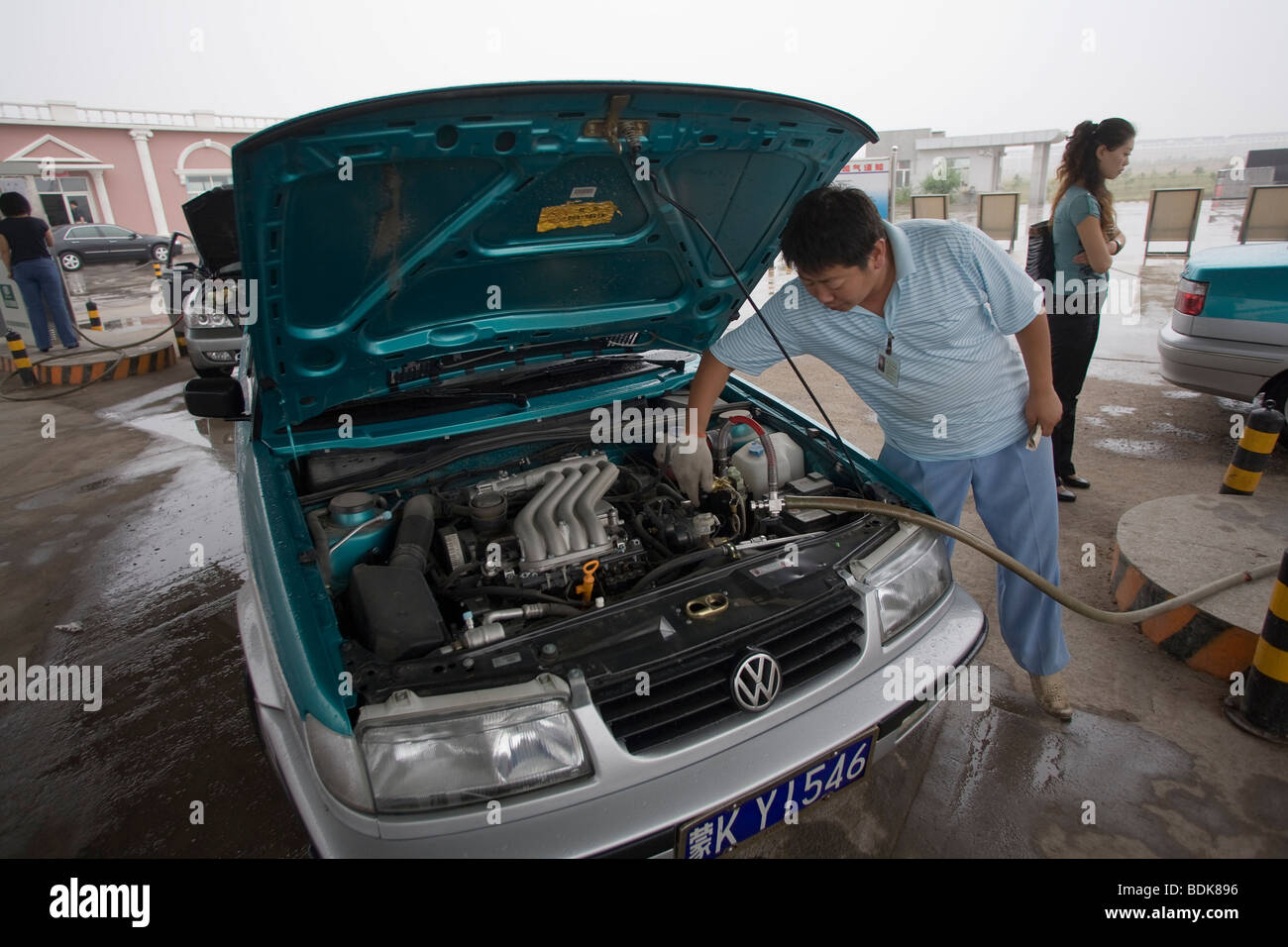 Ordos, Inner Mongolia, China : a taxi driver refills his propane gas tank at a petrol station. The connector is under the bonnet Stock Photo