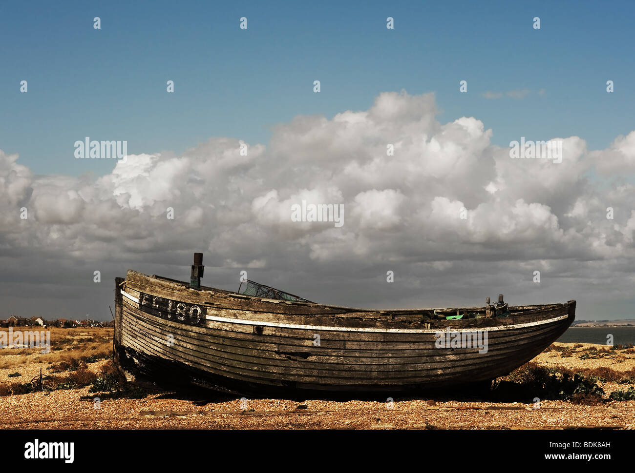 An abandoned wooden fishing boat beached on the shingle at Dungeness in ...