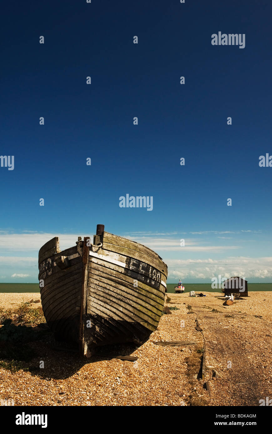 An abandoned wooden fishing boat beached on the shingle at Dungeness in ...