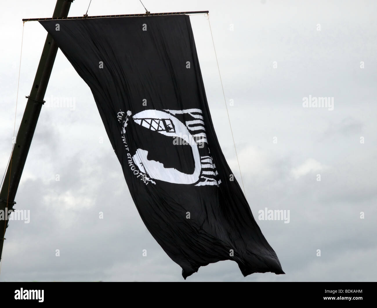 POW MIA flag hanging from a crane high in the sky. The sky is overcast. Stock Photo