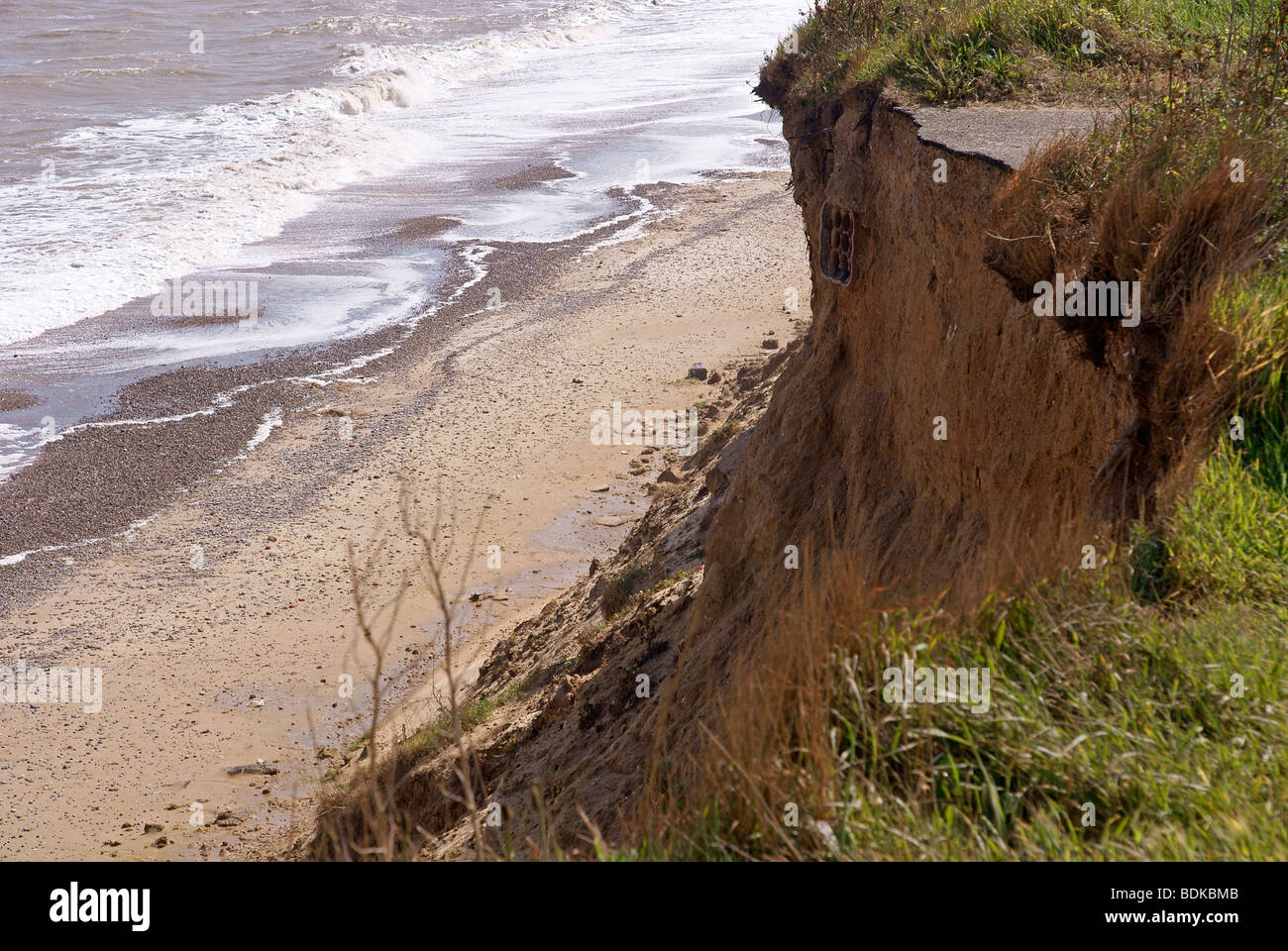 Coastal cliff erosion with exposed and severed drainage pipes under collapsed road Stock Photo