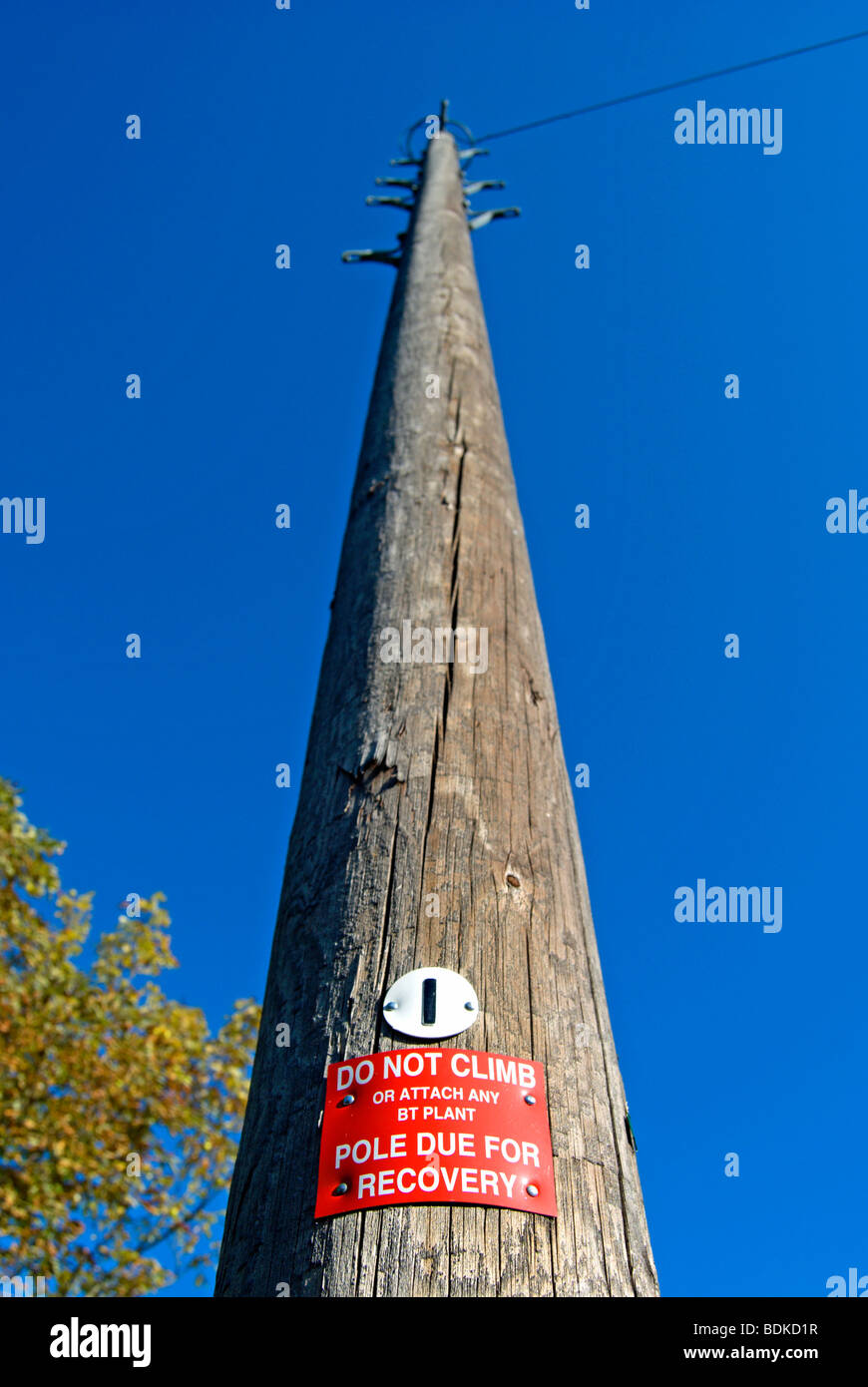 british wooden telegraph pole with do not climb sign and pole due for recovery notice Stock Photo
