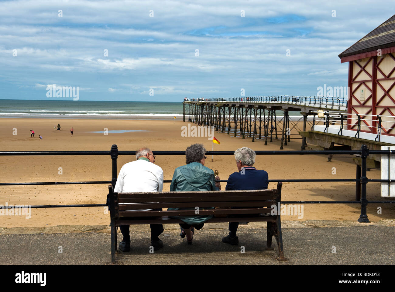 Three People Sitting On A Bench At Saltburn Pier Stock Photo