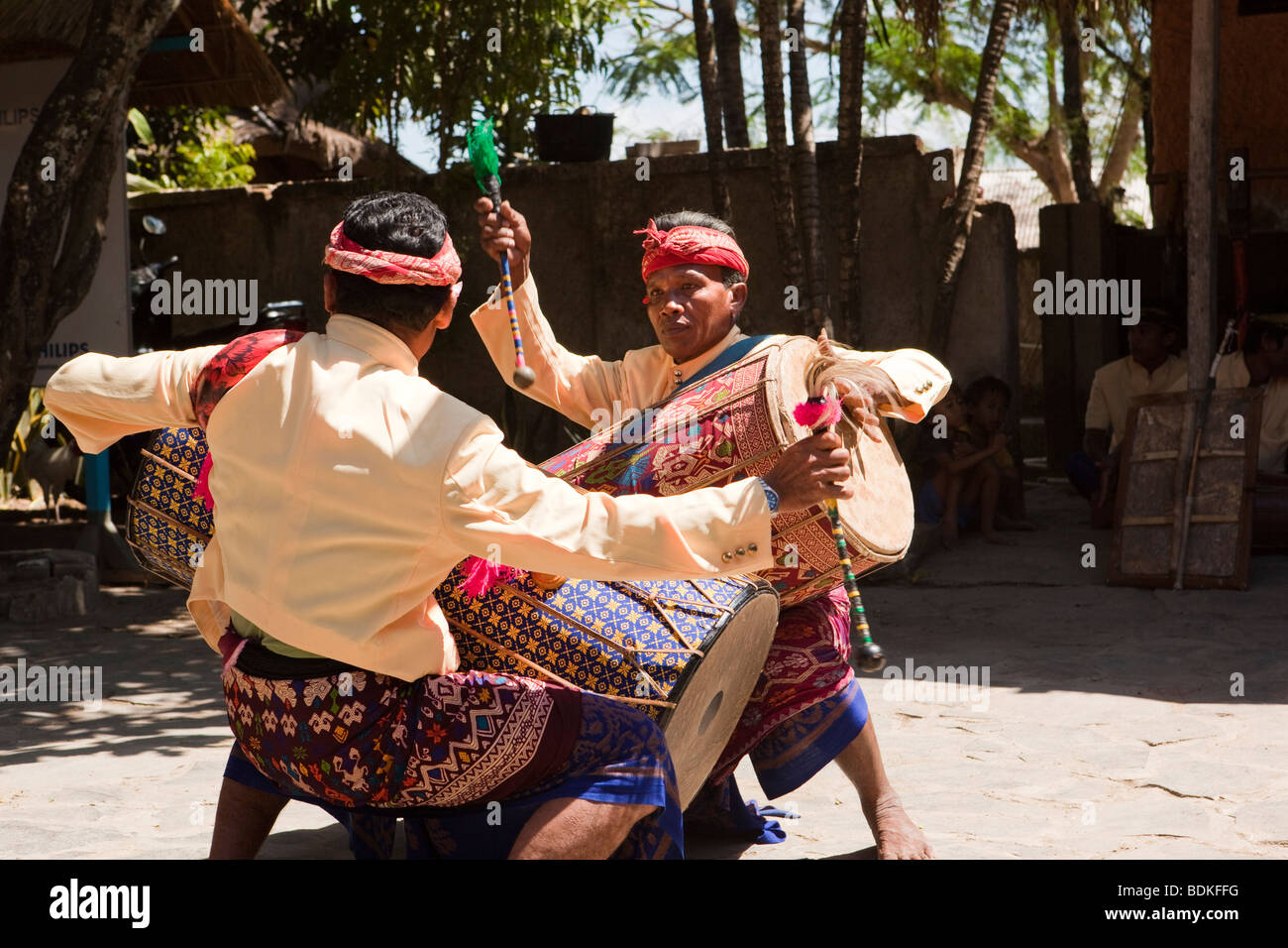 Indonesia, Lombok, Sade, traditional Sasak village, two men drumming to welcome visiting party of tourists Stock Photo