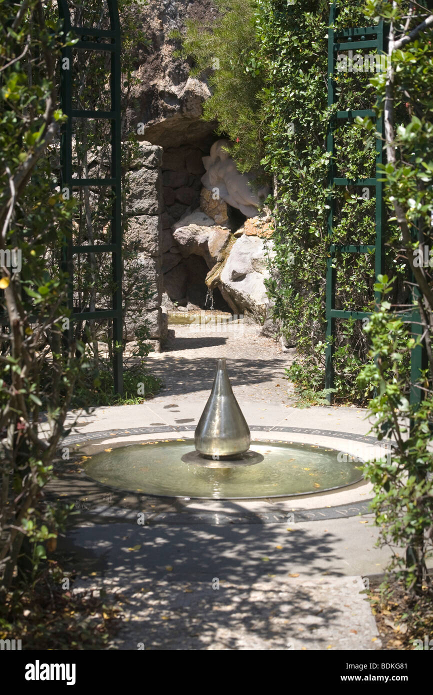 Cone-shaped metal fountain with Aphrodite reclining by a stream in a rock grotto Stock Photo