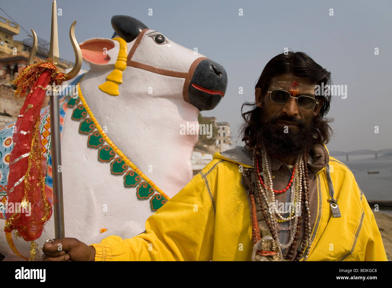 A Sadhu in the Indian city of Varanasi (Benares). He stands in front of a statue of Nandi, Shiva's vehicle. Stock Photo