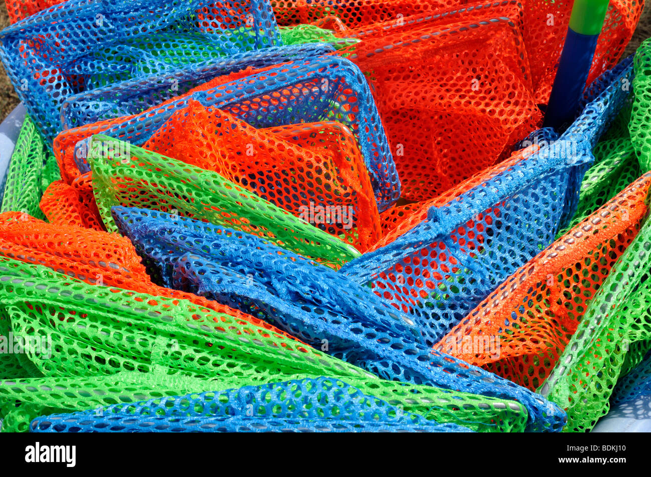 Stack of different colour childrens fishing nets, bamboo sticks