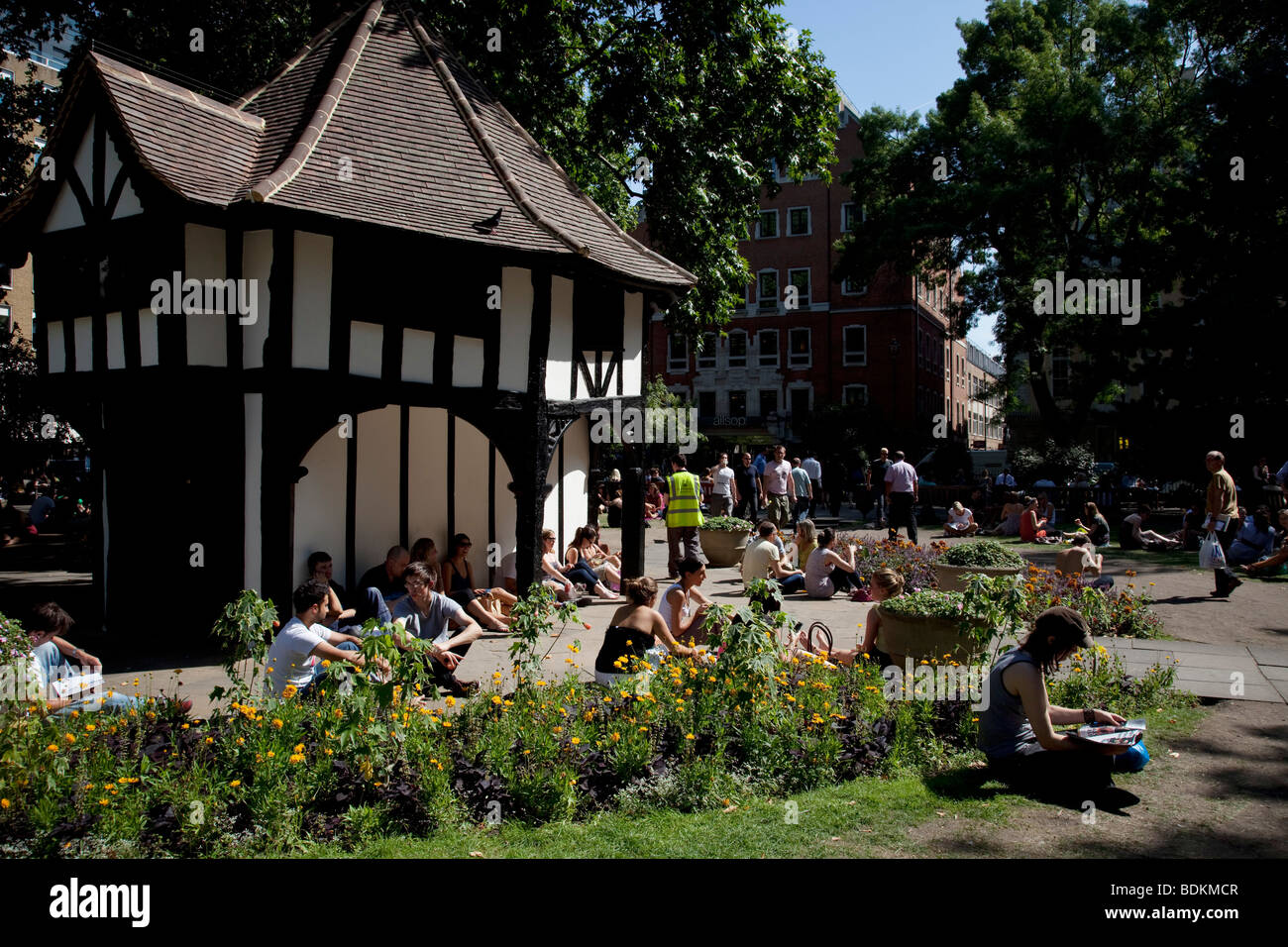 People gather to relax in the sunshine at lunchtime in Soho Square (also known as Soho Beach) in central London. Stock Photo