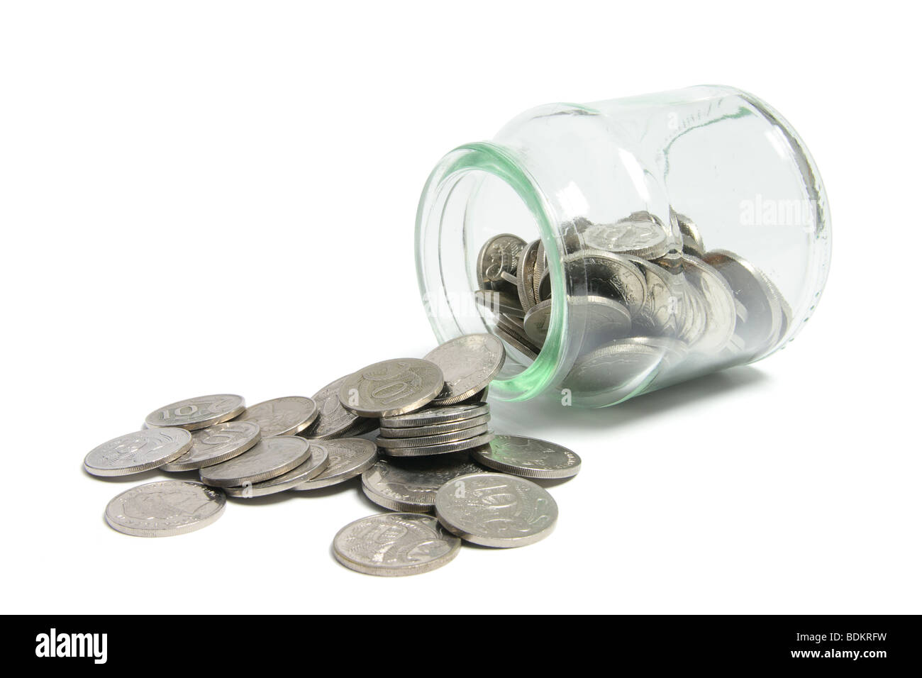 Coins Spilling out of Glass Jar Stock Photo