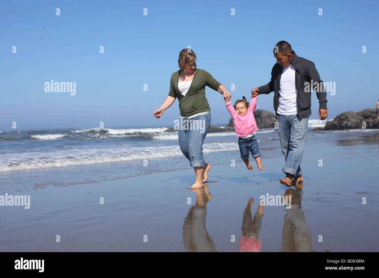 Mother and father swinging young girl at beach Stock Photo