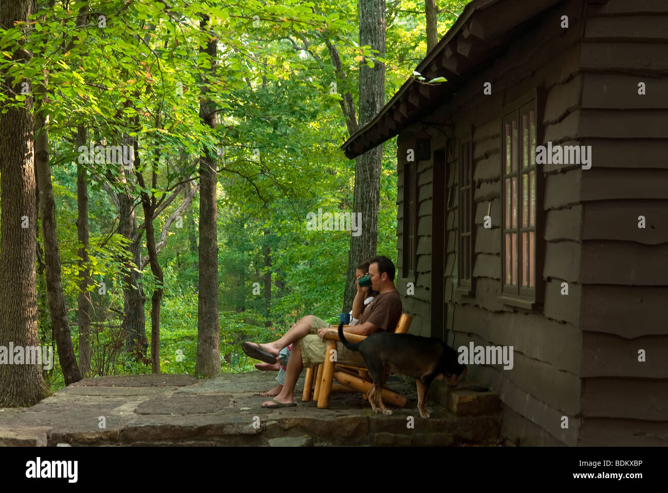 Young couple sitting on the porch of a rustic cabin available for rent in Devil's Den State Park in Arkansas. Stock Photo