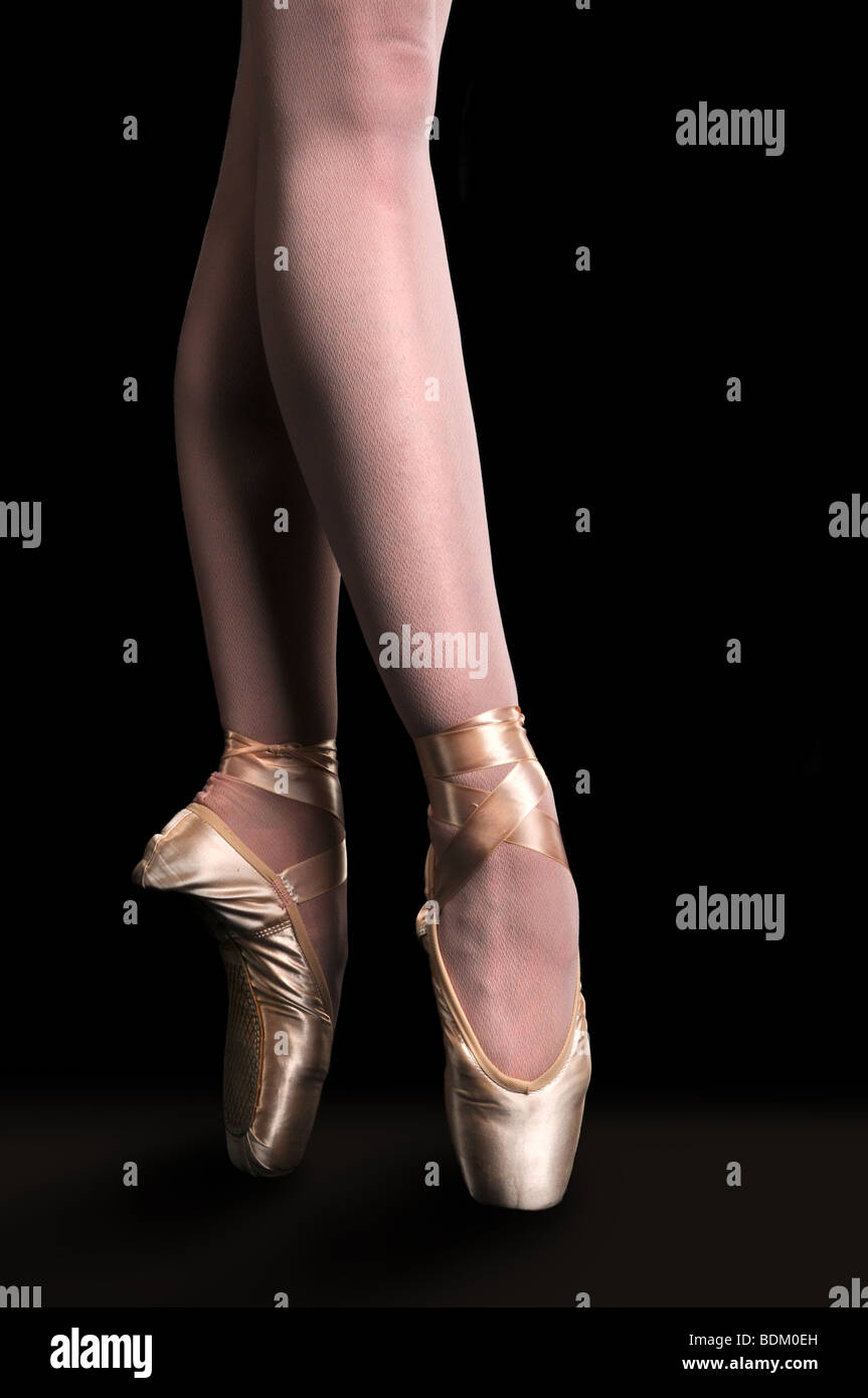 Feet of ballerina dancing in pointe over a dark background Stock Photo