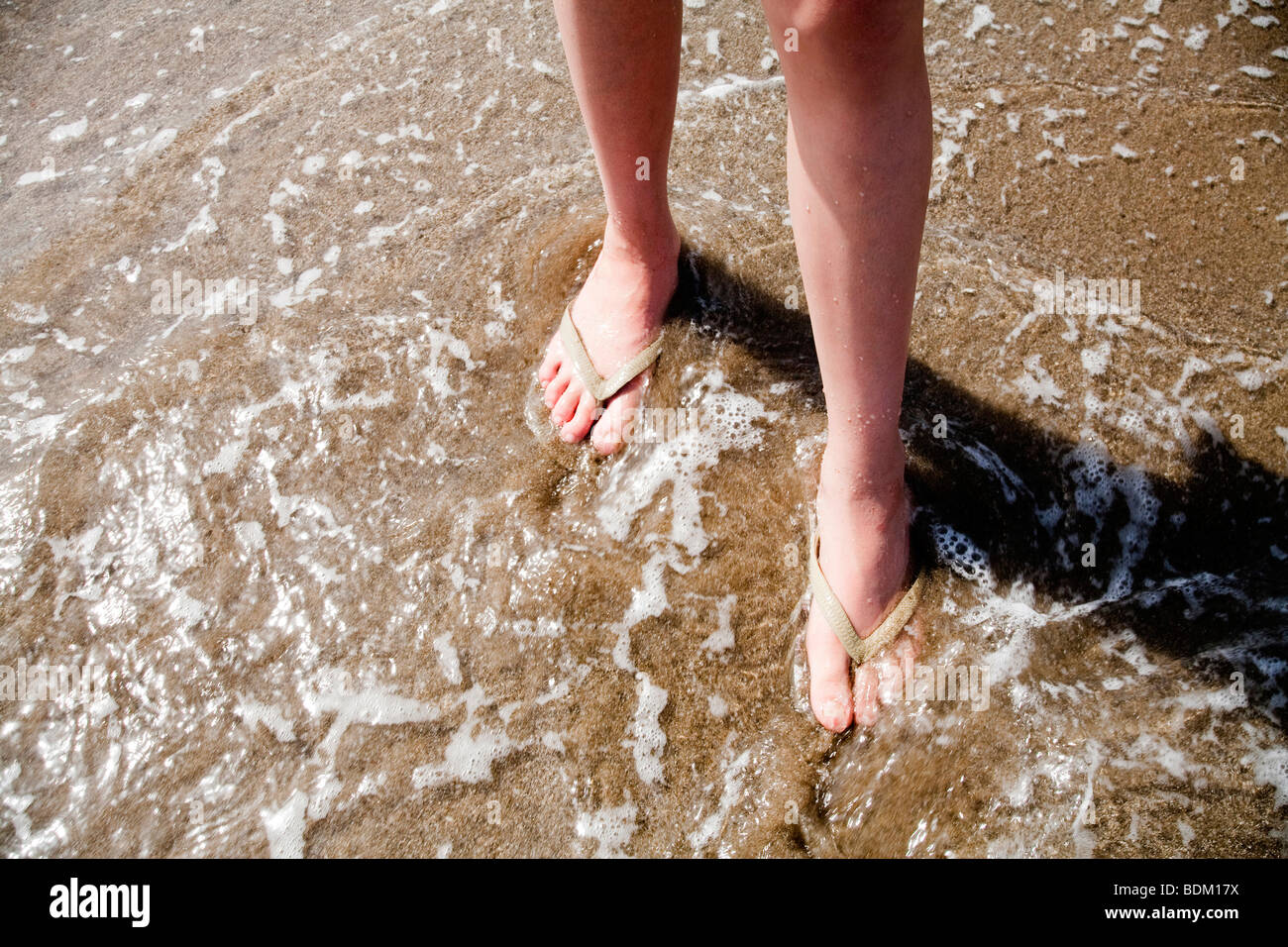 Girls feet walking through the shallow sea wearing flip flops Stock Photo -  Alamy