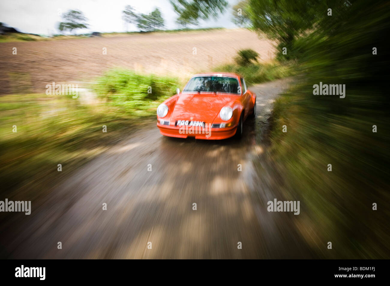 Porsche 911s driving down a country lane with a water splash Stock Photo