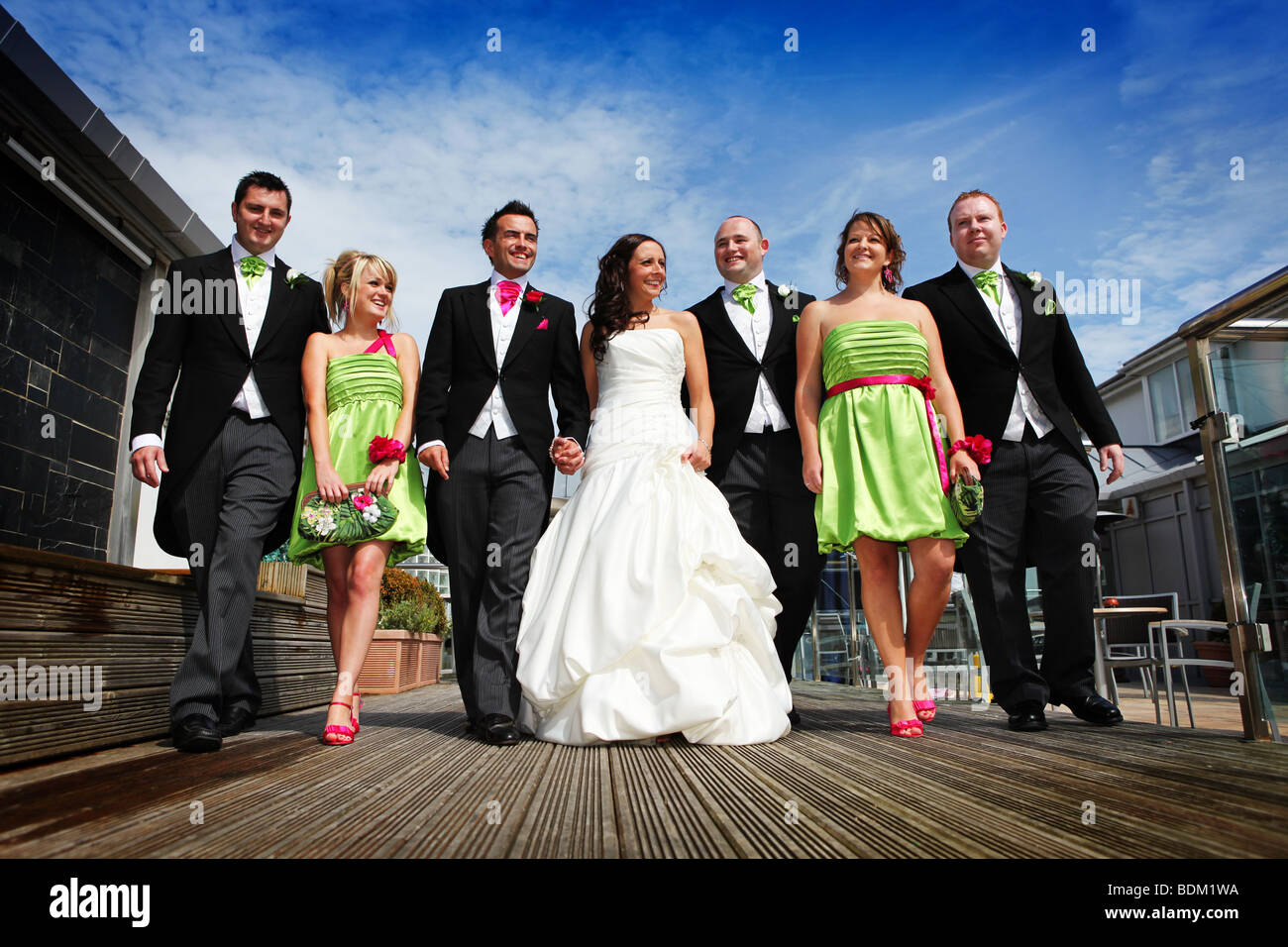 Bride and Groom and bridal party brides maids ushers best man walking hand in hand at a colourful summer wedding unusual angle Stock Photo