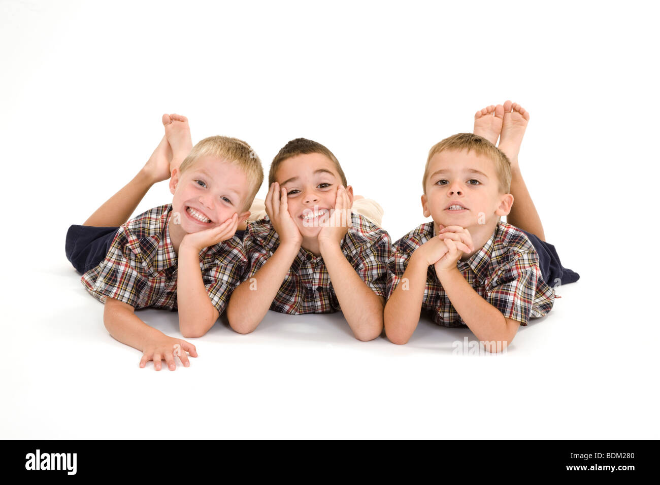Three Caucasian boys laying on a white background and smiling. Stock Photo