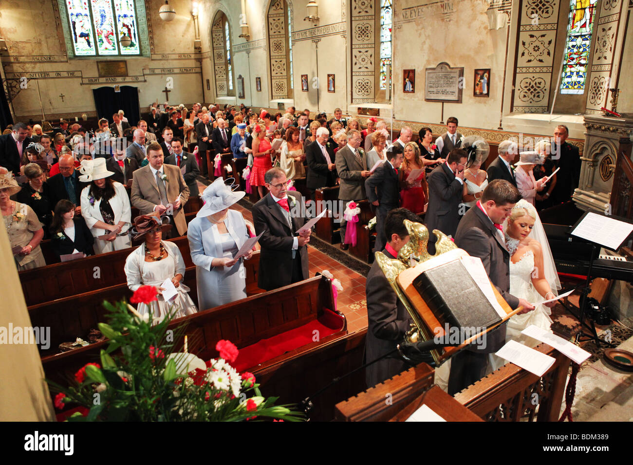 Traditional UK church wedding ceremony bride and groom at altar colourful guests congregation religious ritual Stock Photo
