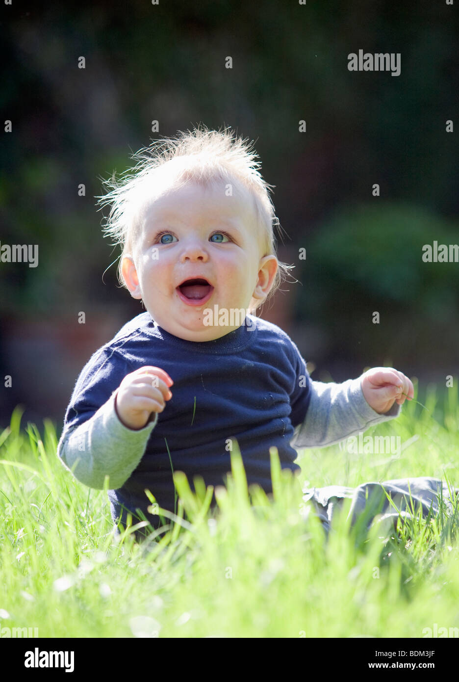A baby boy sitting on grass with a happy expression Stock Photo - Alamy